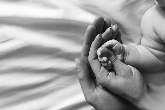 Hands of mother and father holding the child's hand as an idea for newborn pictures