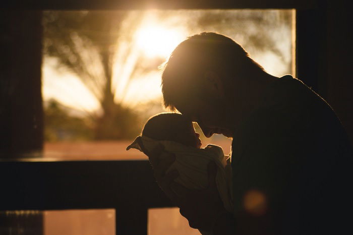 Father holding baby to his head as newborn photo idea