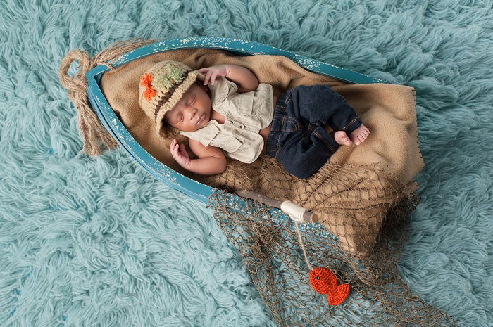 Baby sleeping in miniature boat for a newborn baby photoshoot