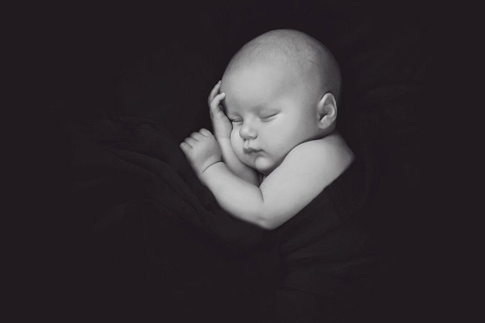 Black and white photo of baby in a blanket as newborn baby photoshoot idea