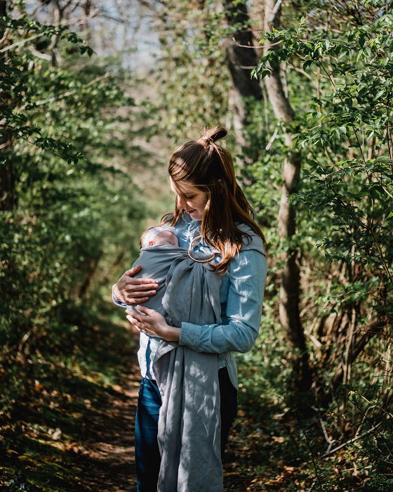 Woman carrying a baby with a papoose outside as newborn photo idea