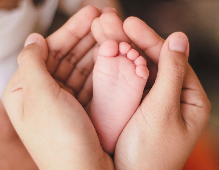 Adults hands cupping a baby's foot as newborn photo idea