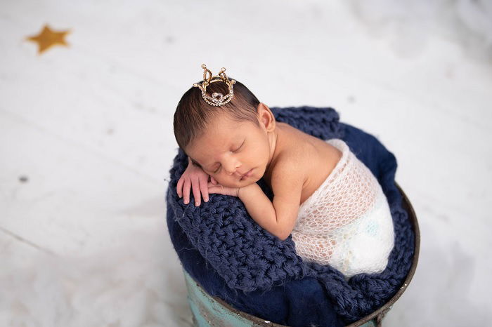 Baby girl with tiny crown on their head as an example of newborn photo ideas