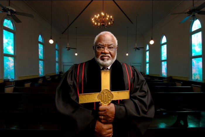 portrait of priest holding a gold cross