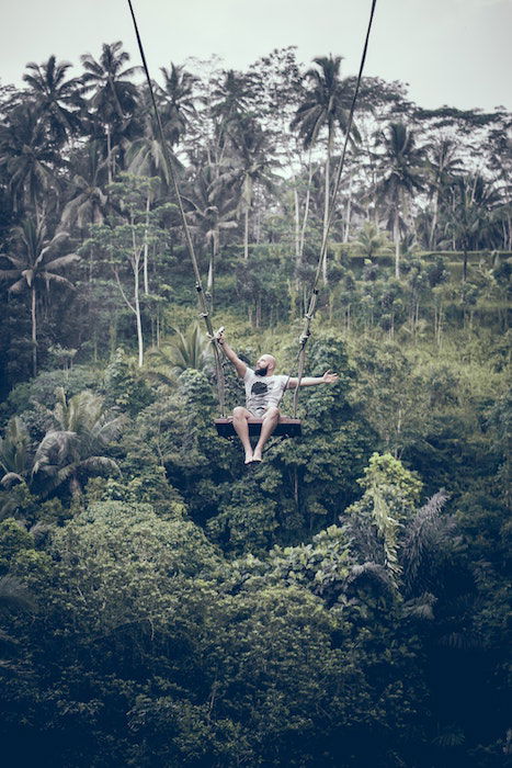 A man taking an extreme selfie on a swing in the jungle