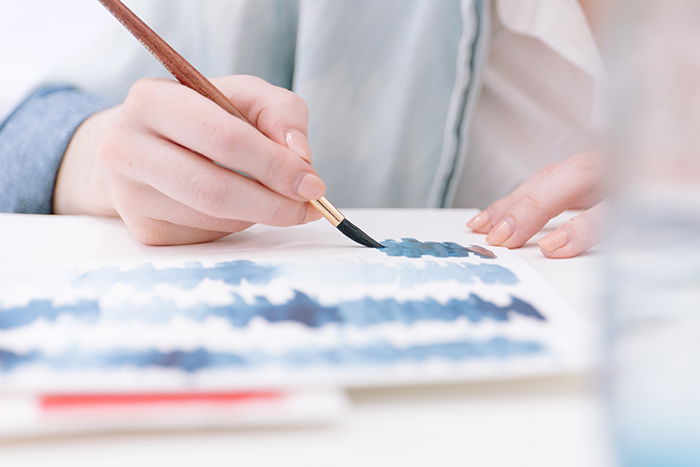 Artist painting with watercolor paints and brush