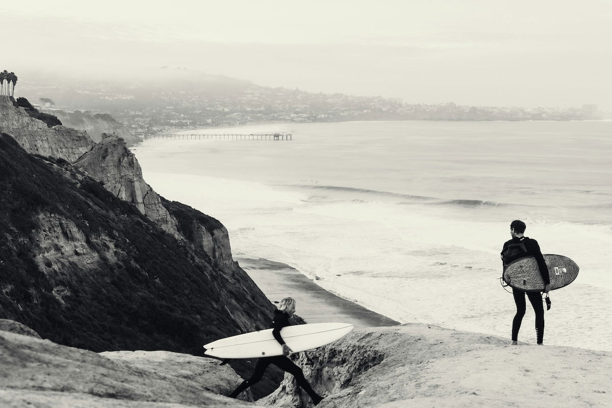 Landscape and seacape image of two surfers with surfboards walking to the beach