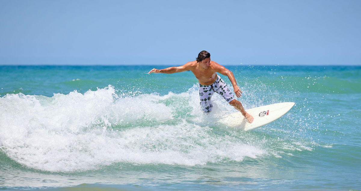 A surfer balancing on a surfboard on a wave coming into shore as an example of surf photography