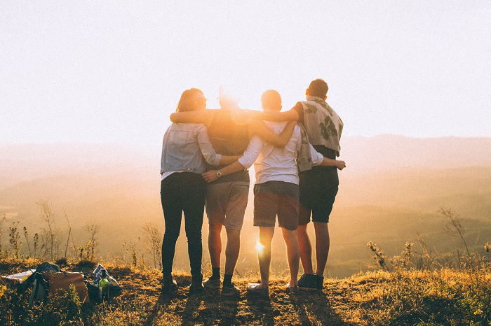 Group of friends with arms over shoulders looking out on a nice view