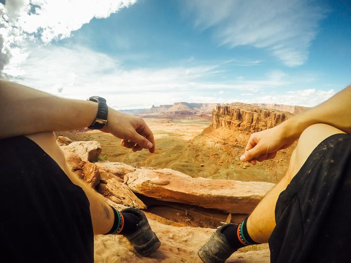 POV shot of man sitting at the top of a canyon, as an example of action photography