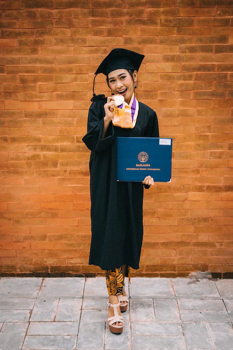 Senior high-school graduate holding a diploma for a senior photoshoot