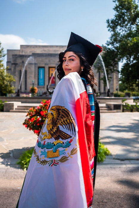 Senior high-school graduate posing with a flag draped over her shoulder