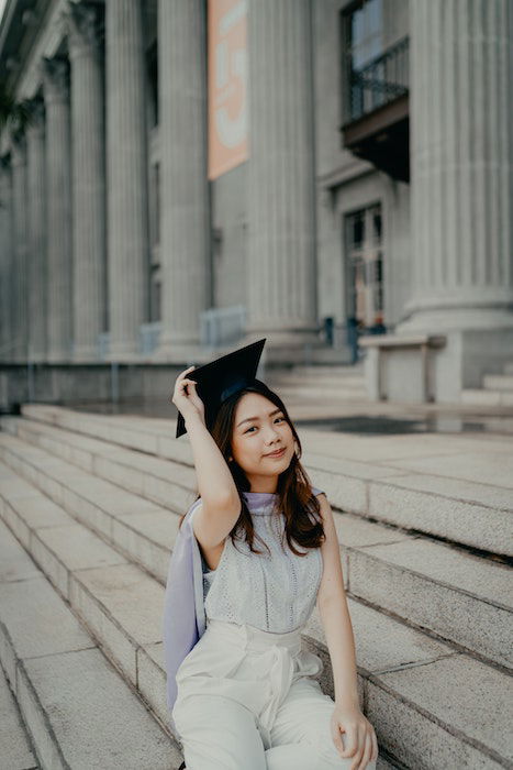 Senior high-school graduate posing on the steps of a building with colonnades in the background