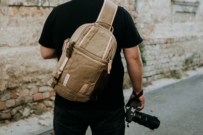 Photographer carrying a camera and a a camera sling bag