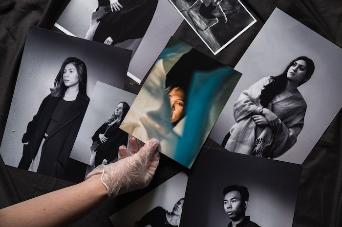 A person holding one of many prints of women portraits