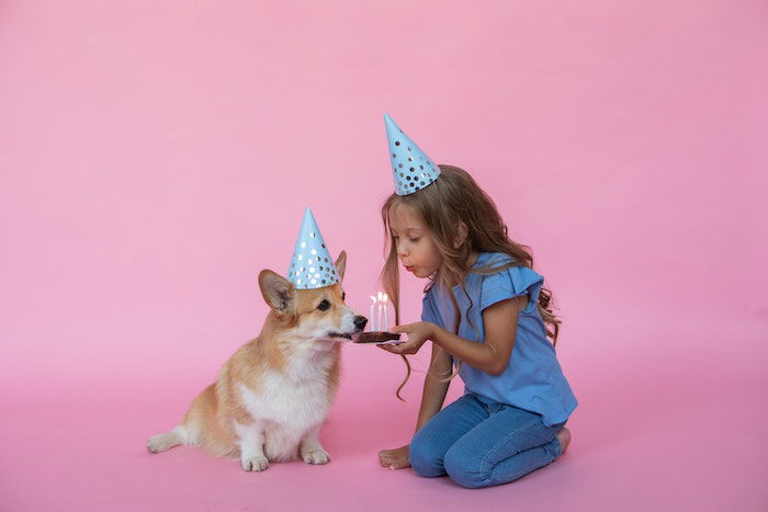 birthday girl blowing out the candles with her dog as a birthday photoshoot idea