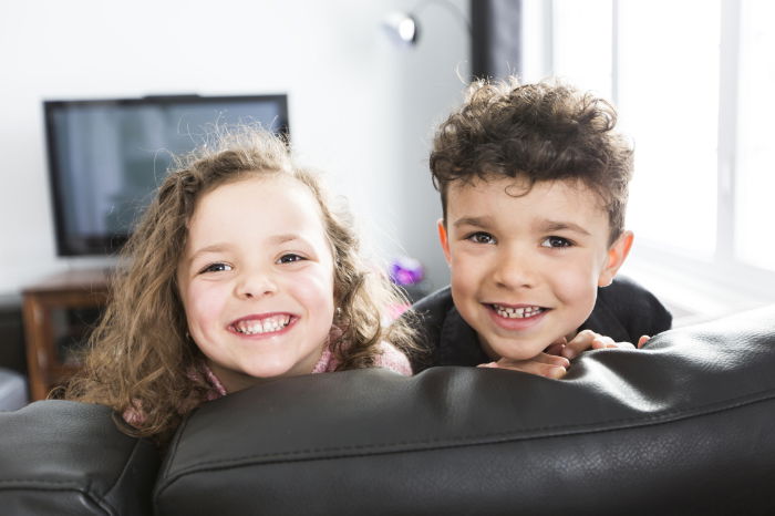 Two cildren looking back over a sofa