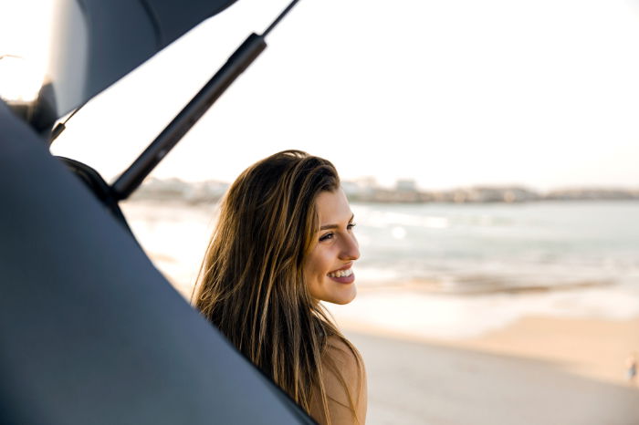 Woman sitting on car tailgate