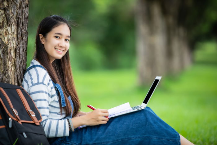 Young woman sitting leaning against a tree