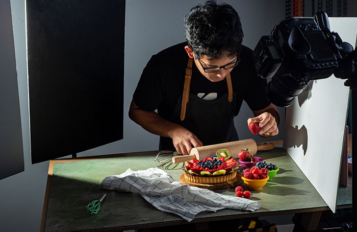 A photographer styling a fruit tart