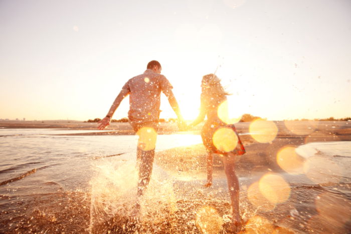 Couple splashing through the sea against the setting sun