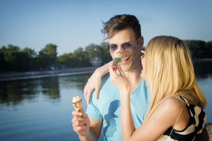 Young woman squashing an ice cream on her boyfriend's nose