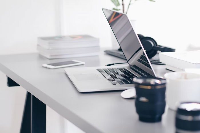 Laptop on a table with a phone and camera lenses