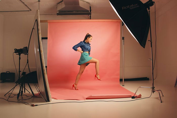 Model posing in a photo studio with a red backdrop