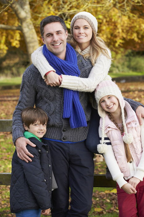 Family posing by a wooden fence in autumn