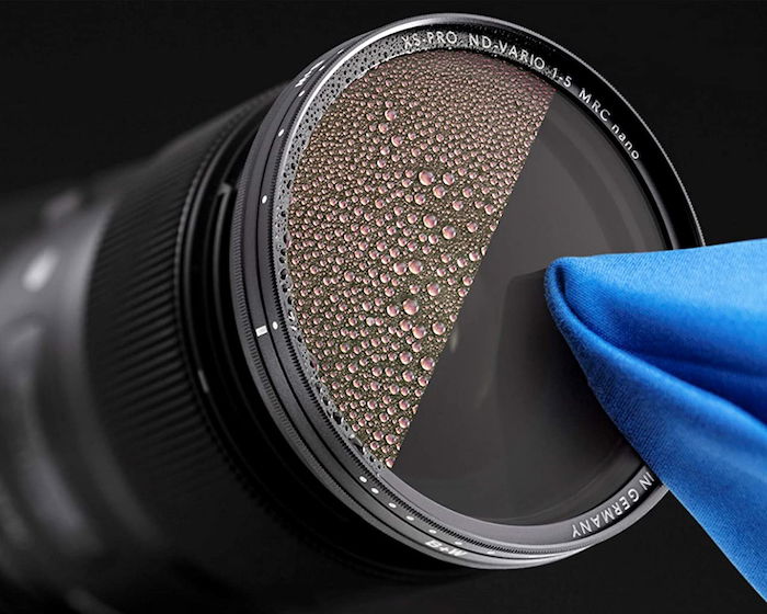 A neutral density filter for landscape photography being cleaned with a cloth showing a protective coating