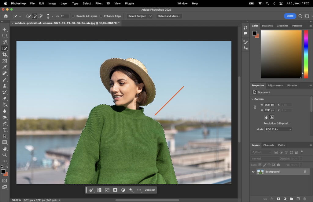 A woman in a straw hat and green sweater standing by a body of water with a selection around her.