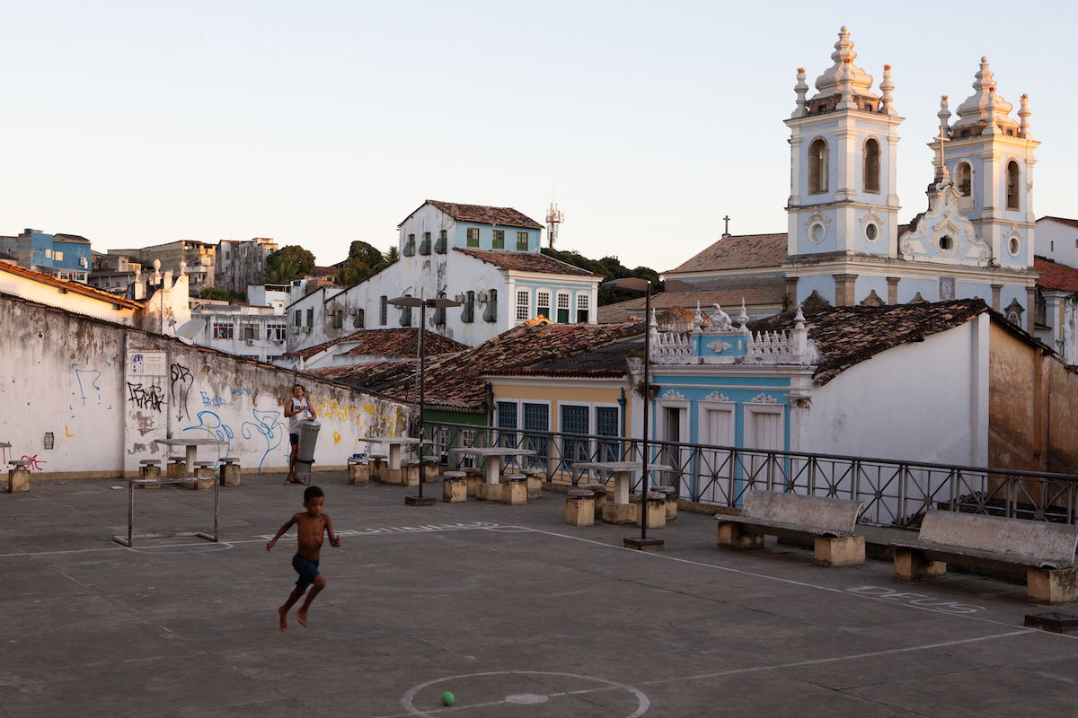 Lightroom RAW image of boy playing in an urban courtyard in front of a church