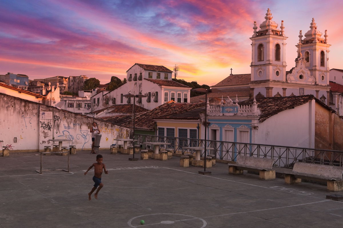 Sky replaced in an image of a boy playing in an urban courtyard in front of a church