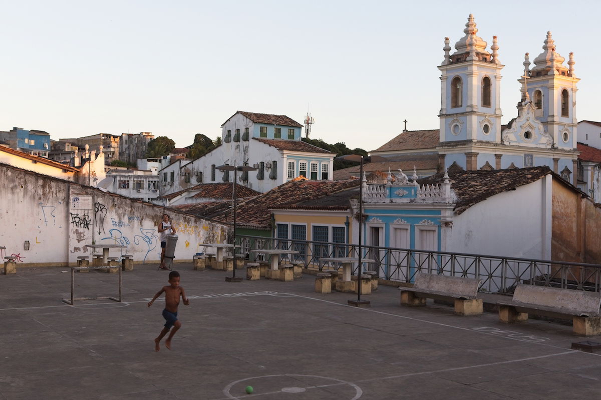 Unedited image of a boy playing in an urban courtyard in front of a church