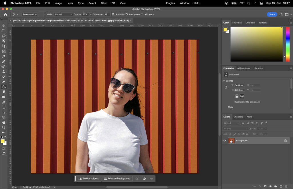 An image editing software displaying a woman standing in front of a red and orange striped background with a white t-shirt.