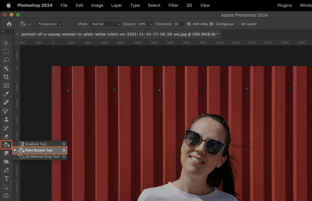 A woman standing against a bright red wall, with the user interface of graphic design software visible. 