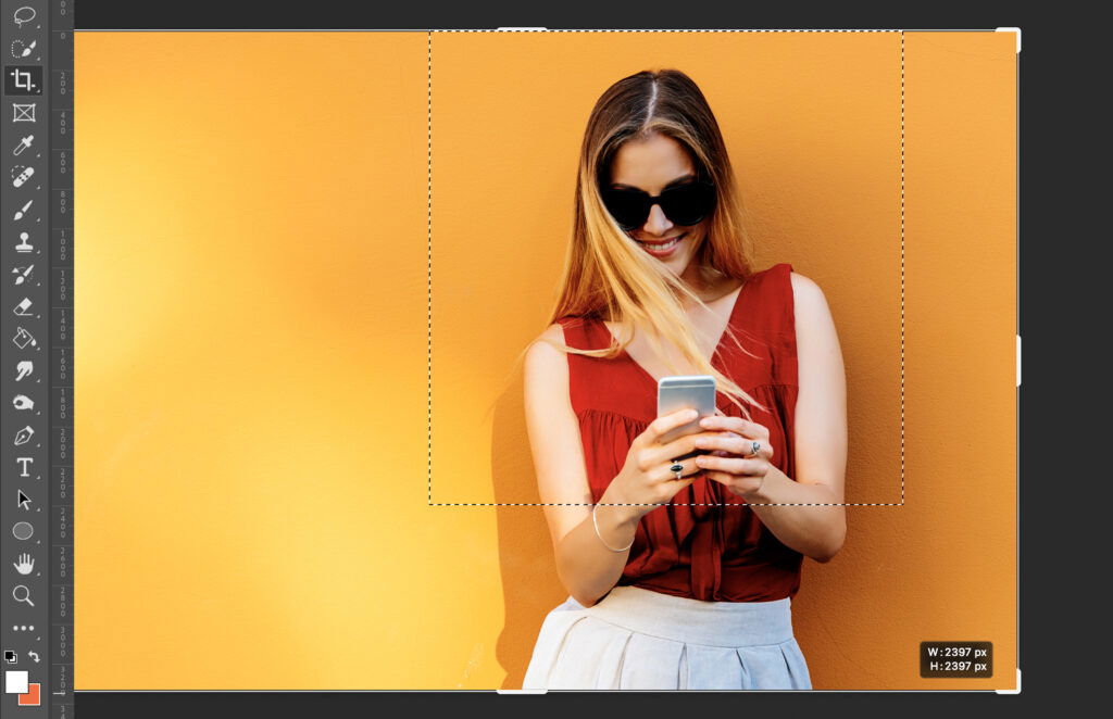 Woman using her cell phone in front of a yellow wall.