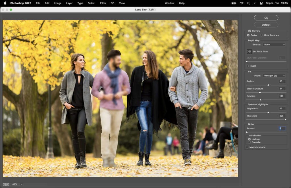 A group of three people smiling, with autumn leaves in the background.