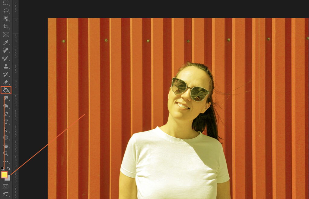 A woman poses confidently in front of a red wooden fence.