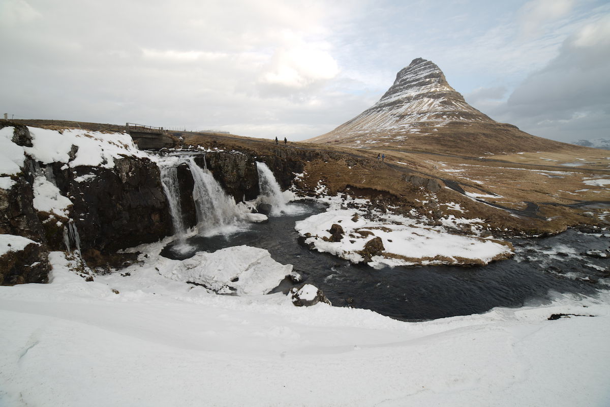 RAW snowy landscape with a waterfall and green mountain in the distance