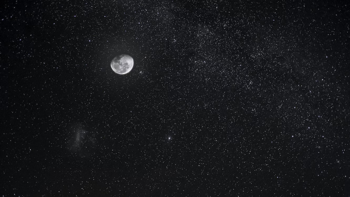 A bright half-moon in a night sky with stars