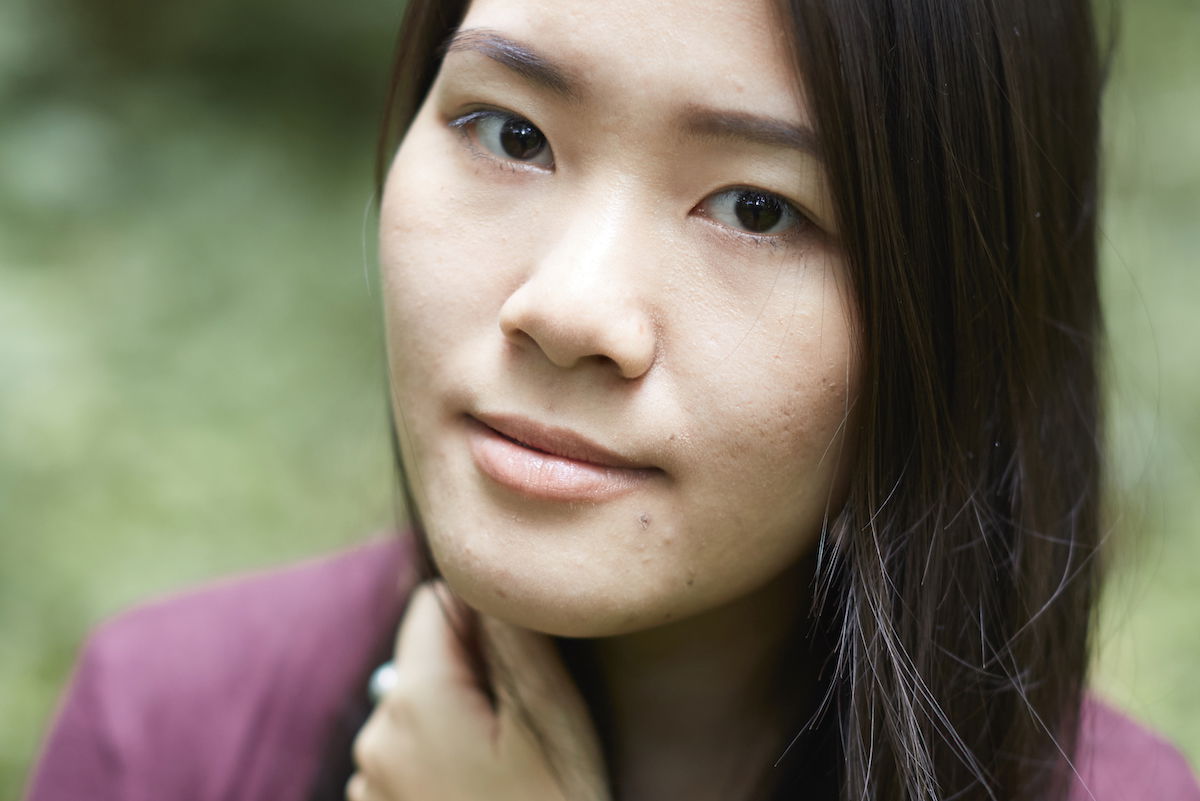 portrait looking down on a woman with a blurred garden background with adjust colors to the skin tones