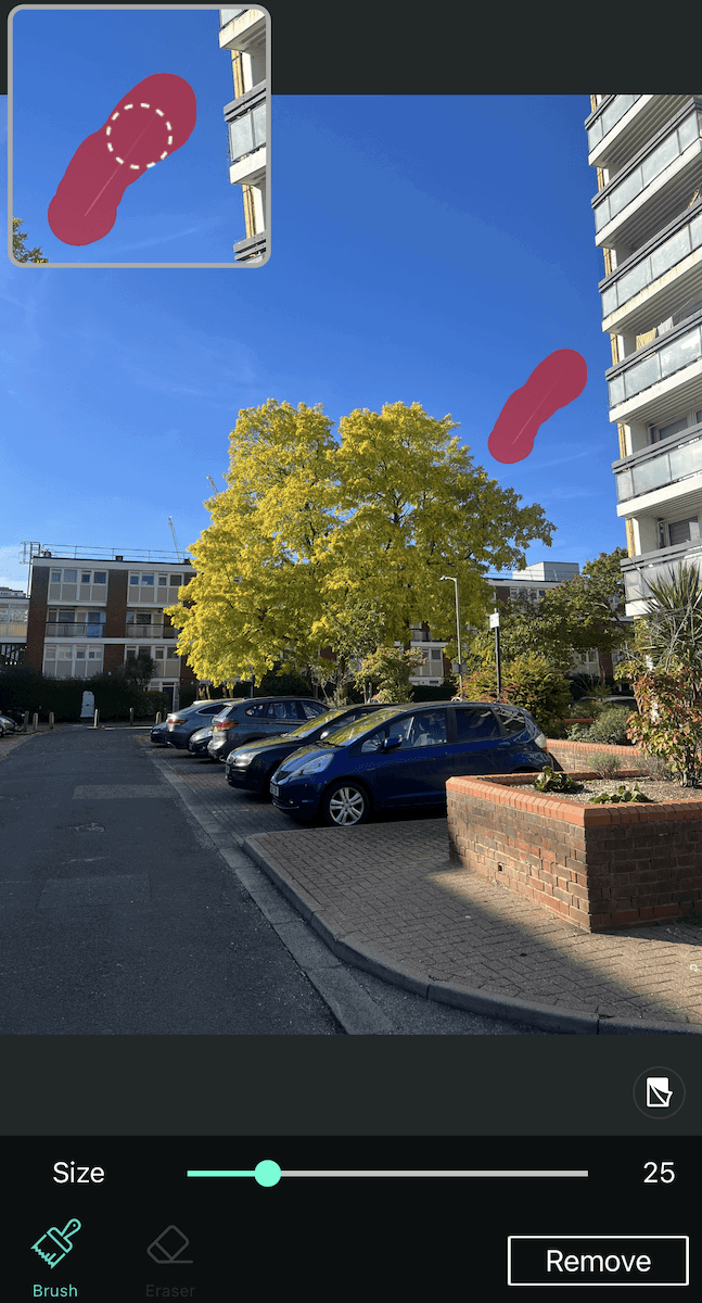 A camera app interface, showing a photo of a street with yellow trees and a blue sky. 