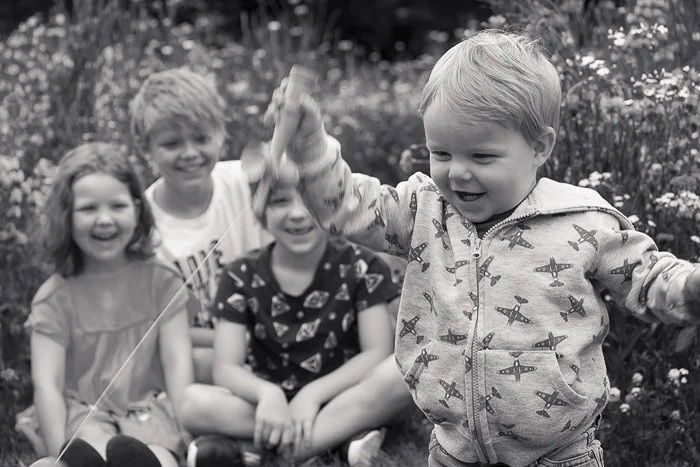 Black-and-white photo or a young child surrounded by older child as an example for family documentary photography