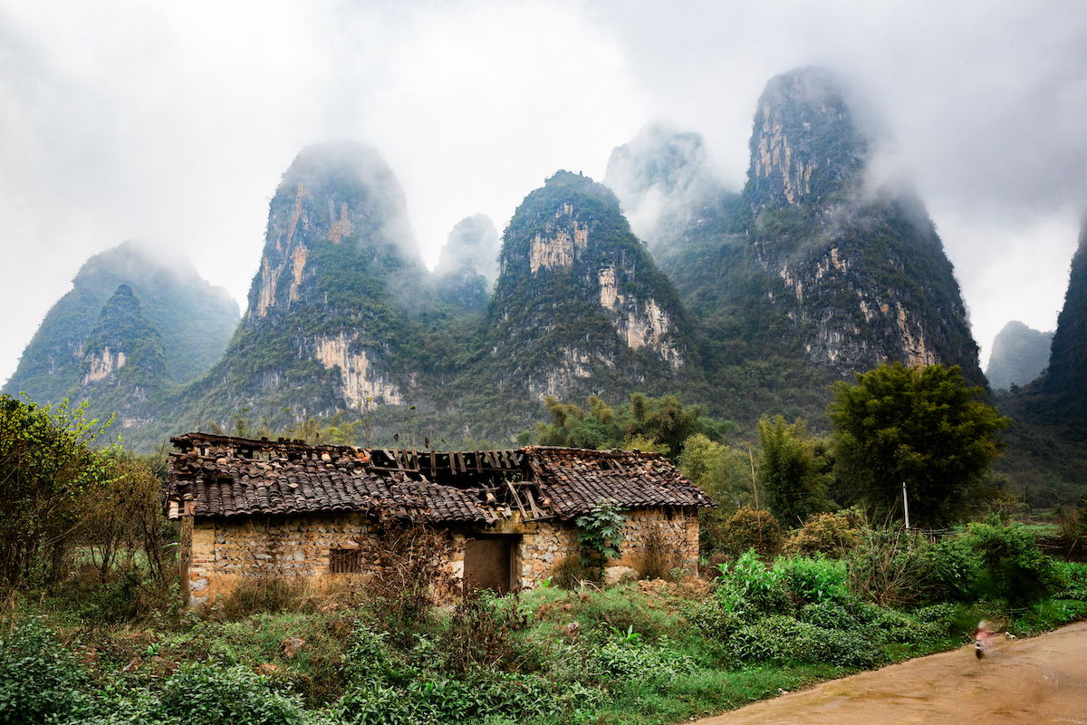 Edited image of a motorcyclist removed from a landscape with a building and karsts