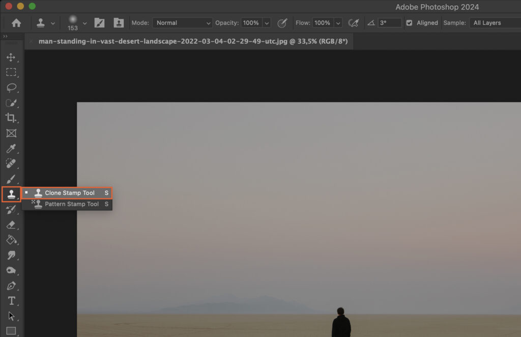 Adobe Photoshop app open, displaying an image of a person standing in an expansive field at sunrise or sunset. 