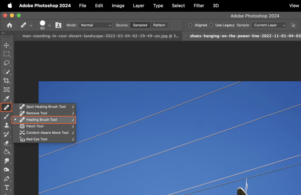 Adobe Photoshop software open, displaying a photo of power lines and a sky with a few clouds. 