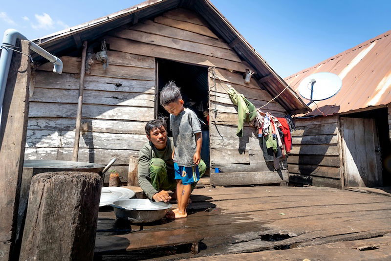 an image of a man washing a boys feet on a wooden porch with a deep depth of field