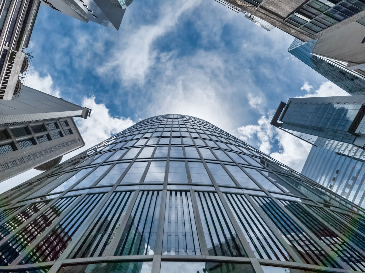 A view. of distorted city buildings, blue sky, and clouds looking up