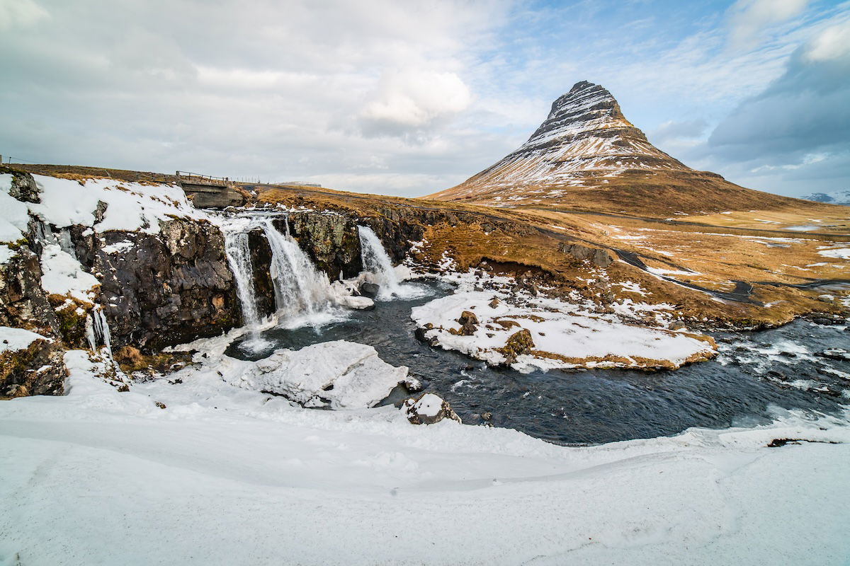 photo of a waterfall and mountain in a partly snowy scene